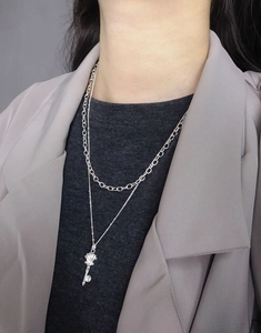 Detail view of double-layered silver S925 necklace with vintage shell key pendant on model