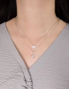 Detail of layered S925 silver necklace with sparkling zircon heart wing and star pendants