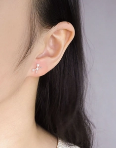 Close-up of S925 sterling silver arrow cross earrings with a small white zircon on ear