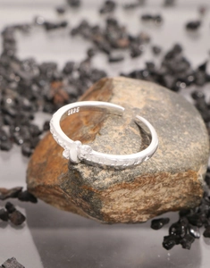 Close-up of S925 sterling silver star embossed open ring on a textured stone