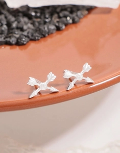 Macro shot of silver cupid arrow earrings with zircon stone on ceramic plate