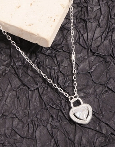 Detailed close-up of S925 silver heart locket necklace with zircon stone on stone background