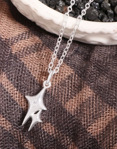 Close-up of S925 sterling silver star pendant necklace with cubic zirconia on a ceramic dish