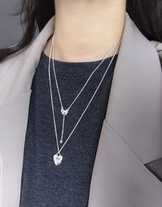 Close-up of S925 sterling silver layered necklace with heart and bow pendants