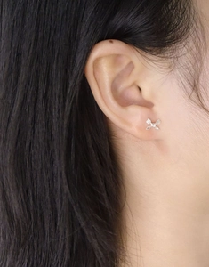 Close-up of S925 silver bow stud earrings featuring a sparkling zircon center on a model's ear