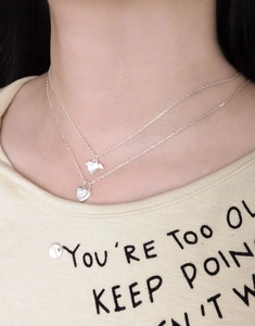 Detail of layered S925 sterling silver heart necklace with zircon wings on a female model