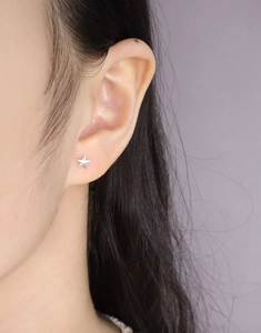 Close-up of minimalist star stud earring in S925 sterling silver worn on ear