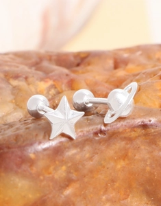 Macro view of S925 sterling silver star and planet screw-back earrings on natural stone