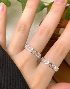 Detail of S925 sterling silver heart rings with hollowed and linked designs on fingers