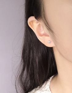 Close-up of S925 sterling silver planet stud earring with ring detail on a model