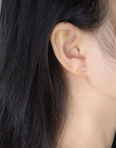 Close-up of a minimalist S925 sterling silver star stud earring worn on the earlobe