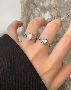 Detail of S925 silver pear-shaped white agate and green gemstone rings on hand