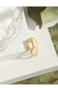 Nahaufnahme eines goldenen Hufeisenrings mit Zirkonia-Inlay auf Stein-Display