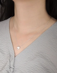 Detailed close-up of S925 sterling silver heart necklace with glowing moonstone on model neck