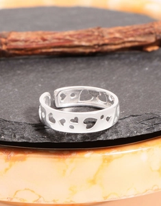 Close-up of a hollow heart-shaped silver ring on a dark stone base with wood details