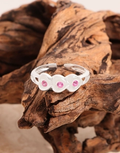 Close-up of S925 silver ring featuring three pink heart stones on rustic wood base