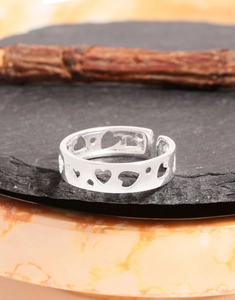 Close-up of polished silver hollow heart pattern on adjustable open band ring