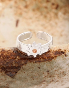 Macro shot of silver sun ring featuring a central amber stone on a ceramic edge