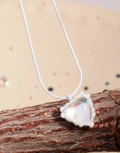 Detailed view of silver heart moonstone pendant resting on natural textured tree bark