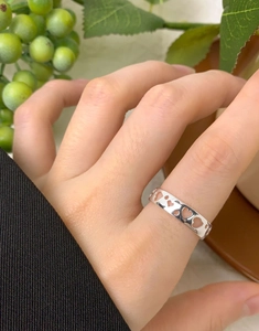 Close-up of minimalist S925 sterling silver ring with hollow heart patterns on finger
