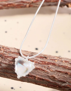 Macro detail of silver heart moonstone pendant necklace on natural branch display