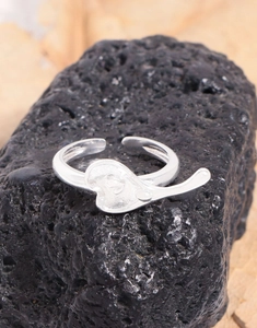 Detailed close-up of a silver heart ring placed on a textured black volcanic rock base