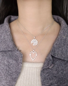 Detail of S925 sterling silver layered necklace with daisy and heart zircon pendants