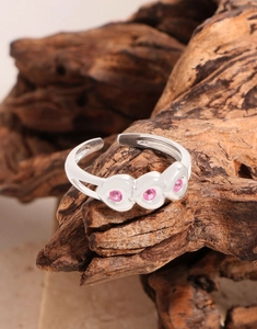 Detail of silver S925 heart ring with pink stones on a natural wooden background