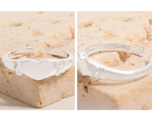Macro detail of S925 sterling silver ring showing heart motif and bow relief engraving