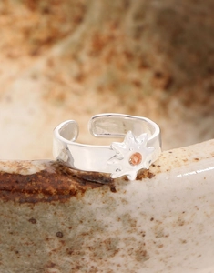 Macro shot of silver sunburst ring with orange gemstone on ceramic edge