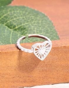Macro shot of an adjustable S925 silver hollow heart ring on a wooden stand with leaves