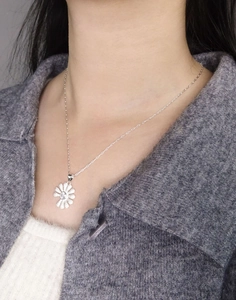 Detail of daisy flower pendant with zircon stone on silver chain worn by a model