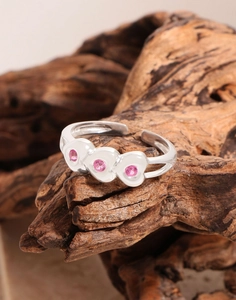 Macro view of adjustable silver heart ring with pink stones on a natural wood block