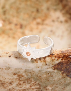 Macro detail of S925 sterling silver sunburst ring with orange gemstone on ceramic