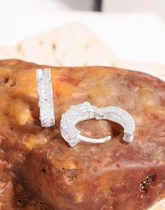 Macro detail of S925 sterling silver hoop earrings with zircon stones on natural stone