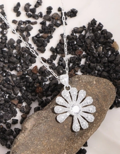 Macro shot of silver daisy pendant with micro-pave zircons on a rectangular link chain