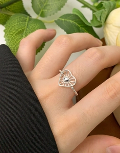 Detail of S925 silver heart ring with radiant lines worn on hand in natural setting