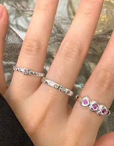 Detailed view of stacked S925 silver rings with heart motifs and pink gemstones