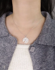Detail of S925 sterling silver daisy pendant with micro-inlaid zircon on a model