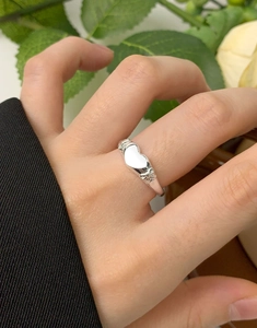 Close-up of S925 sterling silver heart ring with bow design worn on hand with flowers