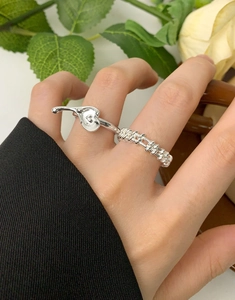 Irregular lava heart ring and rope band set in silver finish on hand with flowers
