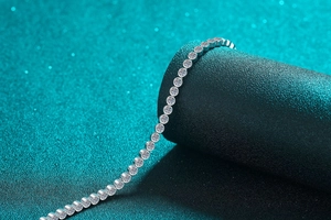 Macro shot of silver moissanite tennis bracelet with round cut stones on textured stand