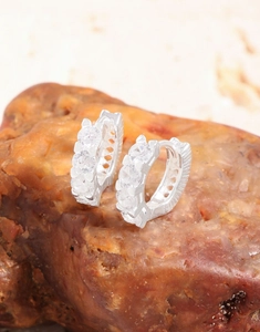 Macro view of S925 silver hoop earrings with three inlaid zircons on a natural stone