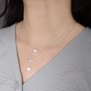 Double-layered 925 sterling silver heart and bow necklace worn on a female model