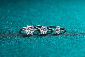 Macro view of three six-prong silver rings with moissanite stones in varying sizes