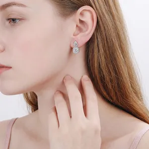 925 silver drop earrings with pear and square cut moissanite worn by an elegant model