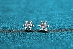 Macro di orecchini a fiocco di neve in argento con moissanite su sfondo glitter blu scuro