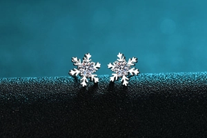 Dettaglio di orecchini a fiocco di neve in argento S925 con moissanite su sfondo blu