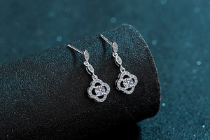Makroaufnahme von S925 Silber Kleeblatt-Ohrhängern mit Moissanit vor dunkelblauem Bokeh