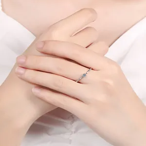 Close-up of S925 silver ring with 10-point moissanite and blue sapphire accents on finger